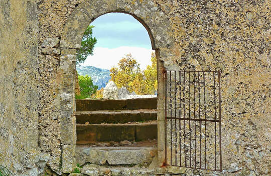 Opening The Gate of Forgiveness: Making Love and Redemption Possible An open gate in a stone wall, opening up to a beautiful nature scene.