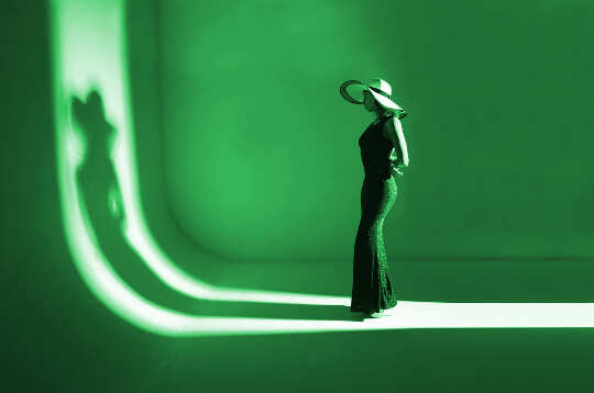 Befriending the Shadow: Transforming Darkness Into Light a model standing on a runway facing her shadow... all in green