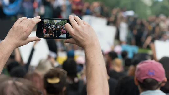 To Weed Out Fake News, A Public-Led Approach Just Might Work someone taking a picture in a crowd