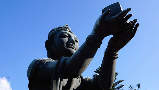 The Triumvirate of Money, Spirituality, and Service buddha statue holding up a gift to the heavens