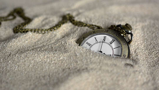 "I'll Do It Tomorrow" -- The Quicksand of Procrastination a pocket watch semi-buried in the sand