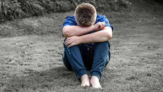 How To Recognize Our Conditioning -- and Release It boy sitting on the sand with his head on his knees