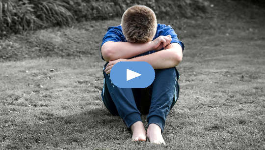 How To Recognize Our Conditioning -- and Release It boy sitting on the sand with his head on his knees