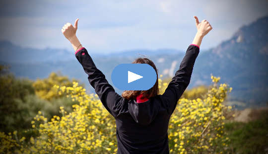 How To Walk The Fearless Path woman looking out over a valley with her two hands in the air with thumbs up