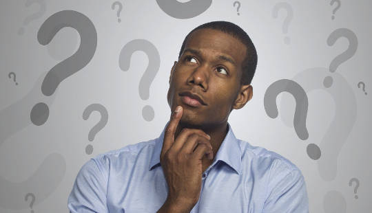 5 Misconceptions About Creativity That Could Be Holding You Back man with a finger on his chin looking up at a backdrop of question marks