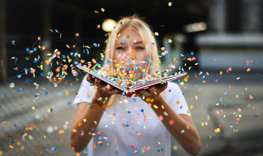 True or False? "There Are No Coincidences" woman blowing confetti off of an open book