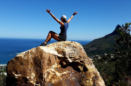 Relax and Enjoy—for a Strong Finish! hiker sitting on top of a huge rock with arms up in the air in triumph