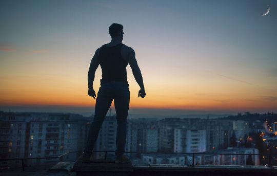 The Most Dangerous Animal of All a silhouette of a man with clenched fists standing on a rooftop overlooking the city