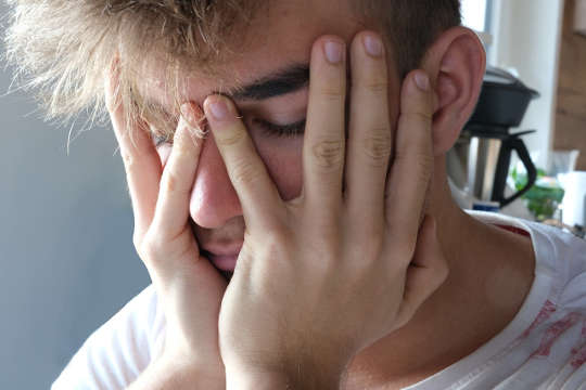 How to Stop Feeling Overwhelmed and Start Feeling Calm young man with yees closed and with his face in his hands