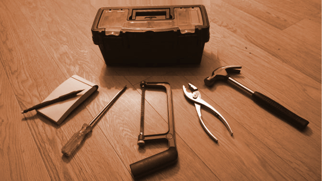tookbox with 5 tools spread out around it: notepad, screwdriver, hacksaw, pliers, hammer