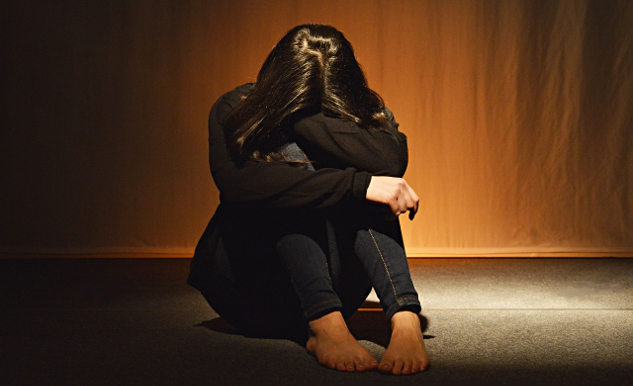 The Feared 6-Letter Word woman sitting on the floor with her face covered by her arms