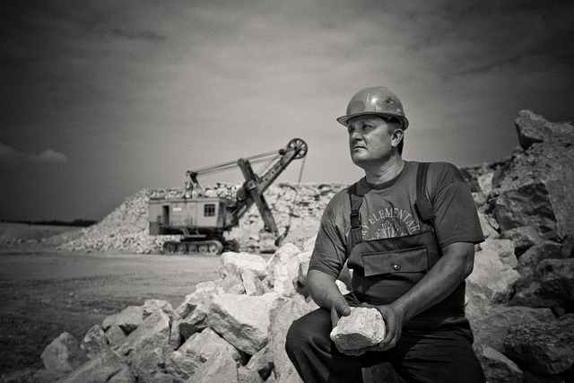 Deal with Your Shadow and Other Negative Forces man sitting holding a big rock on a construction site