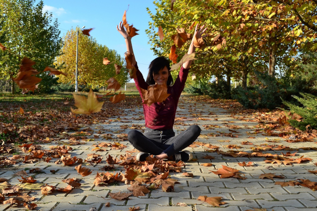You Too Can Manifest Your Best Life Woman sitting outside with arms up in a gesture of happiness and success.