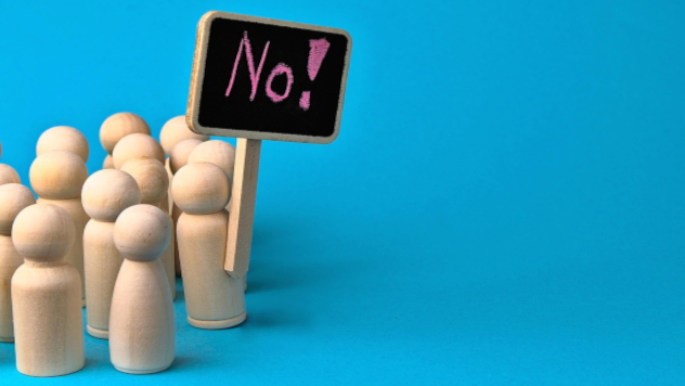 Surviving Democracy wooden figures of people holding up a sign that reads: "No!"